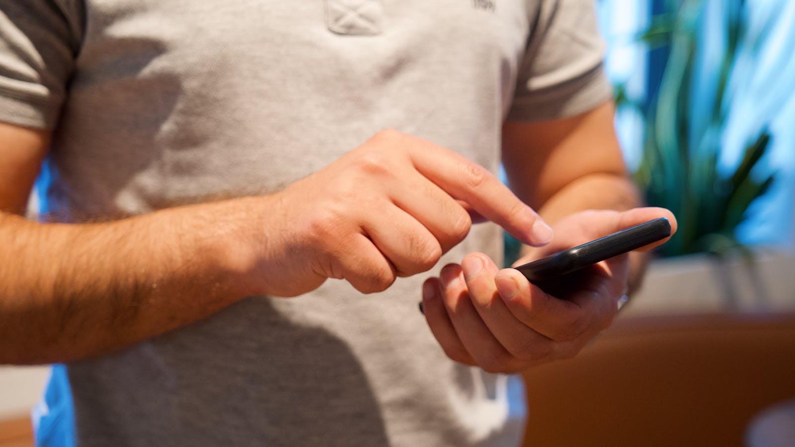 Gülümseyen bir adam elinde bir telefon tutuyor, etrafında internet ve sohbet simgeleri var