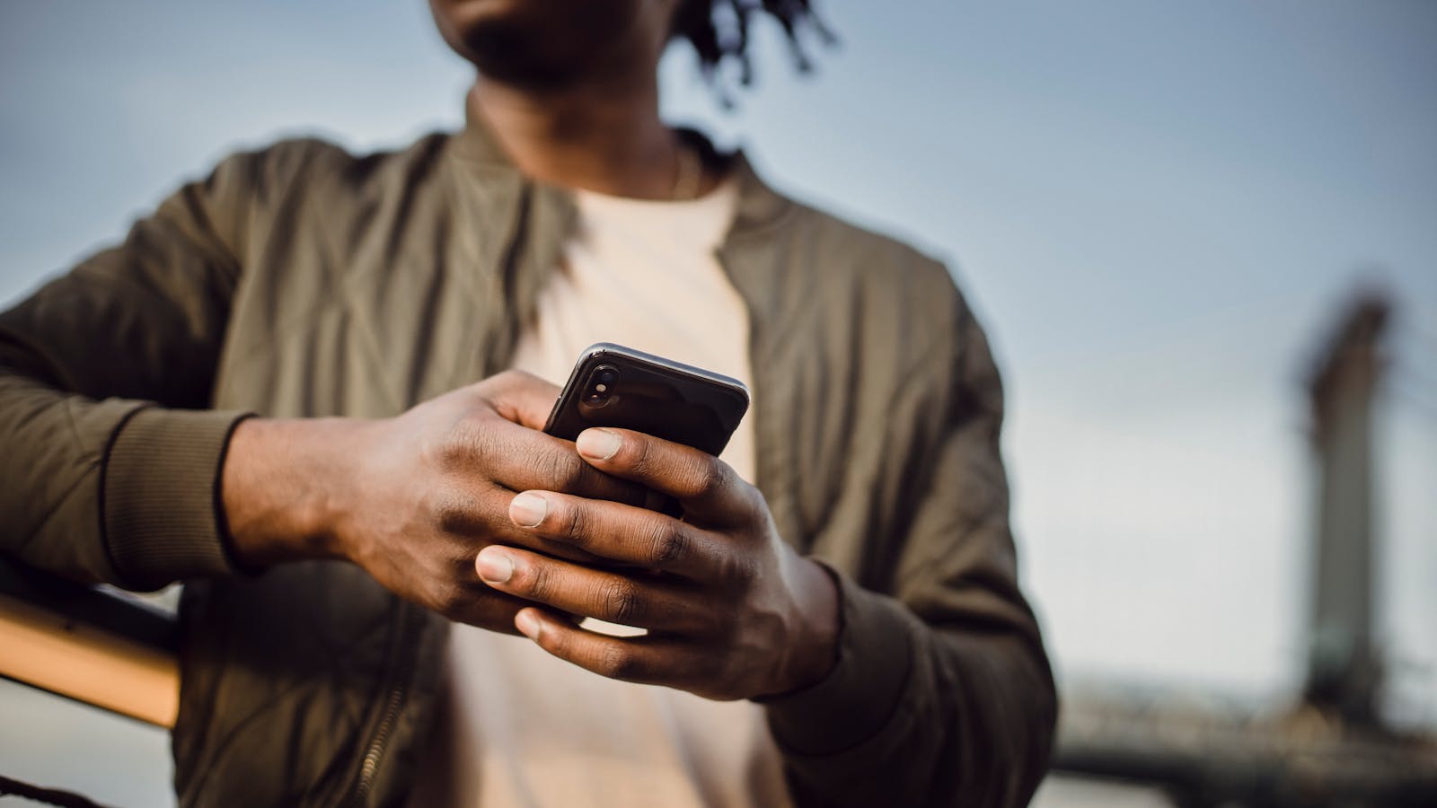 Adam elinde bir telefon tutuyor ve telefonda WhatsApp logosu görünüyor